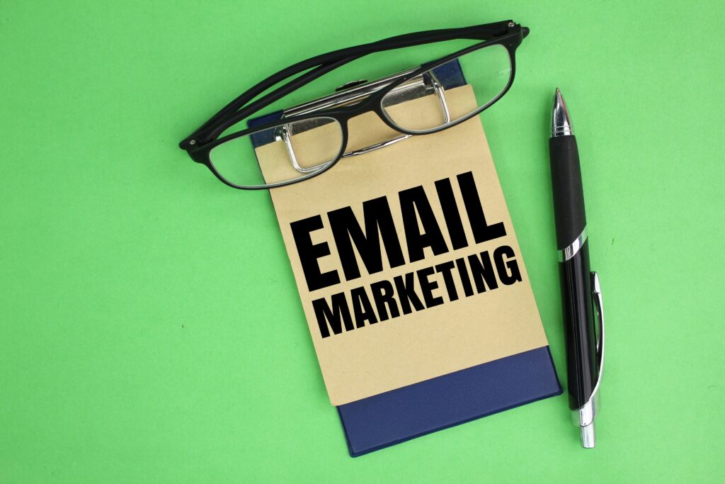 A notepad labeled EMAIL MARKETING sits on a green surface with a pair of eyeglasses resting on top and a black pen beside it, symbolizing the essentials for building an Irish brand through smart digital strategies.