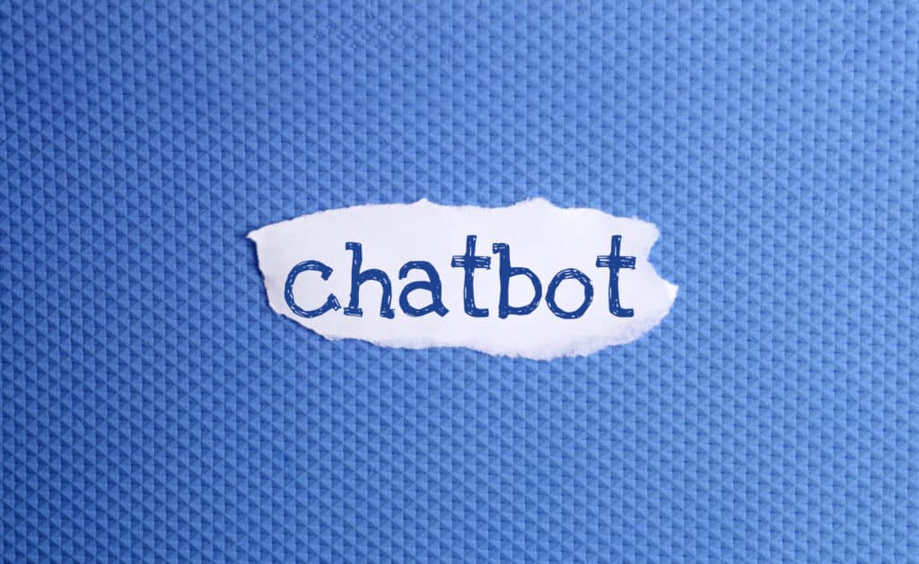A torn piece of white paper with the word chatbot written in blue letters is placed on a textured blue background, evoking creativity and innovation—key elements in building an Irish brand.