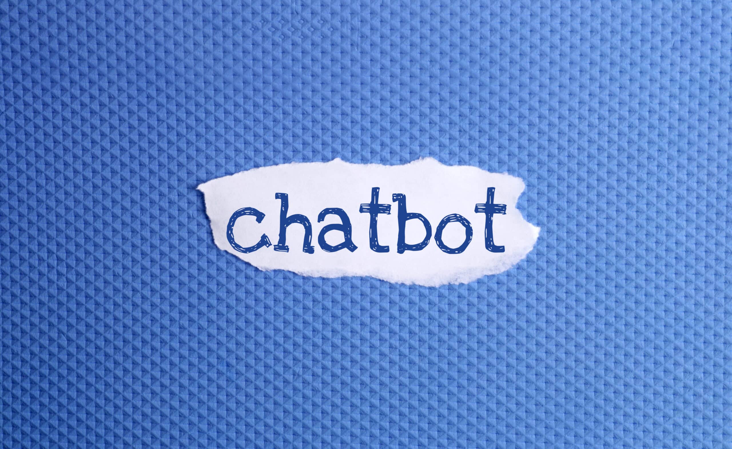 A torn piece of white paper with the word chatbot written in blue letters is placed on a textured blue background, evoking creativity and innovation—key elements in building an Irish brand.