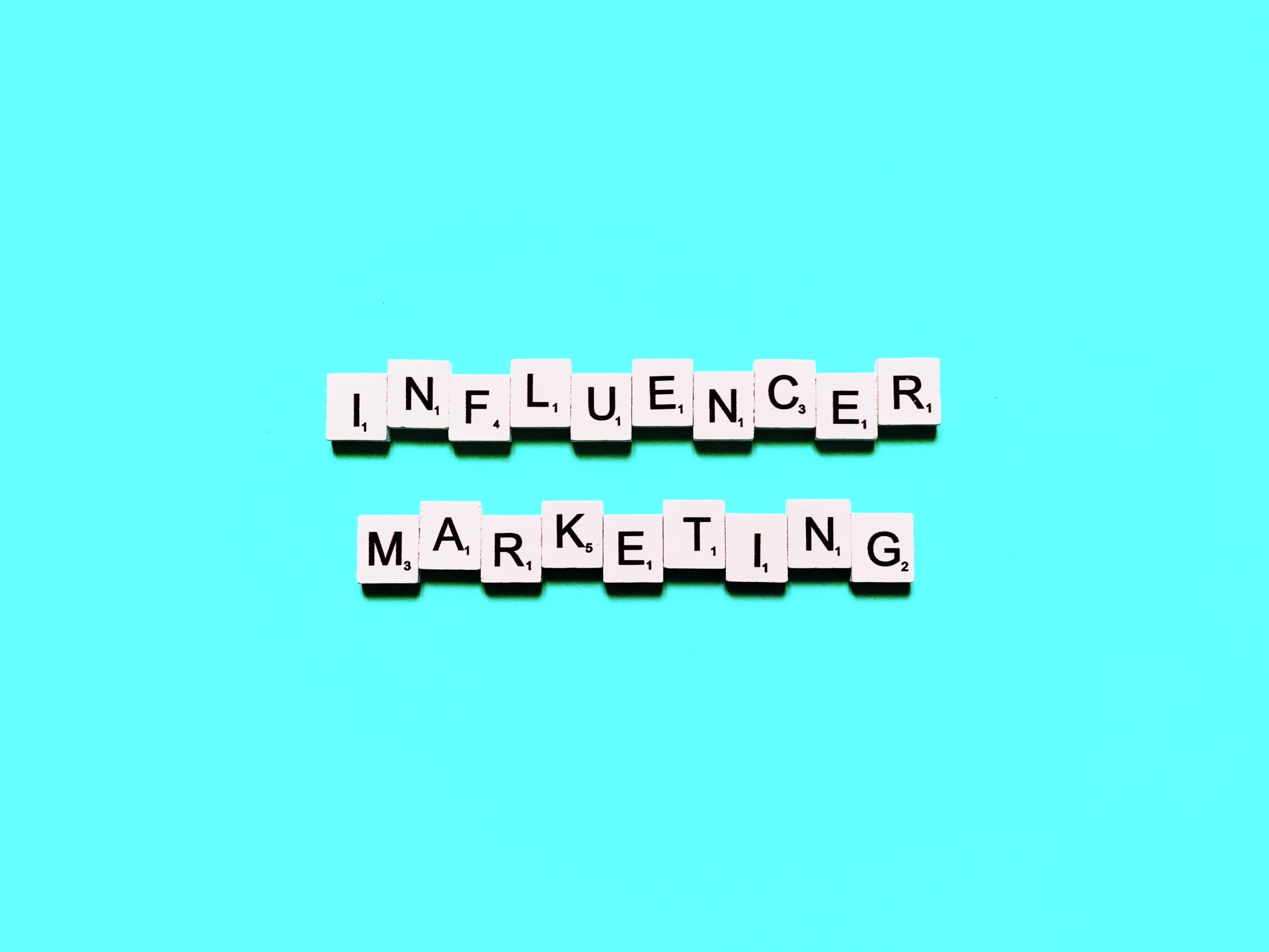 Letter tiles spelling INFLUENCER MARKETING are arranged in two rows on a bright turquoise background, capturing the creativity and strategy behind building an Irish brand.