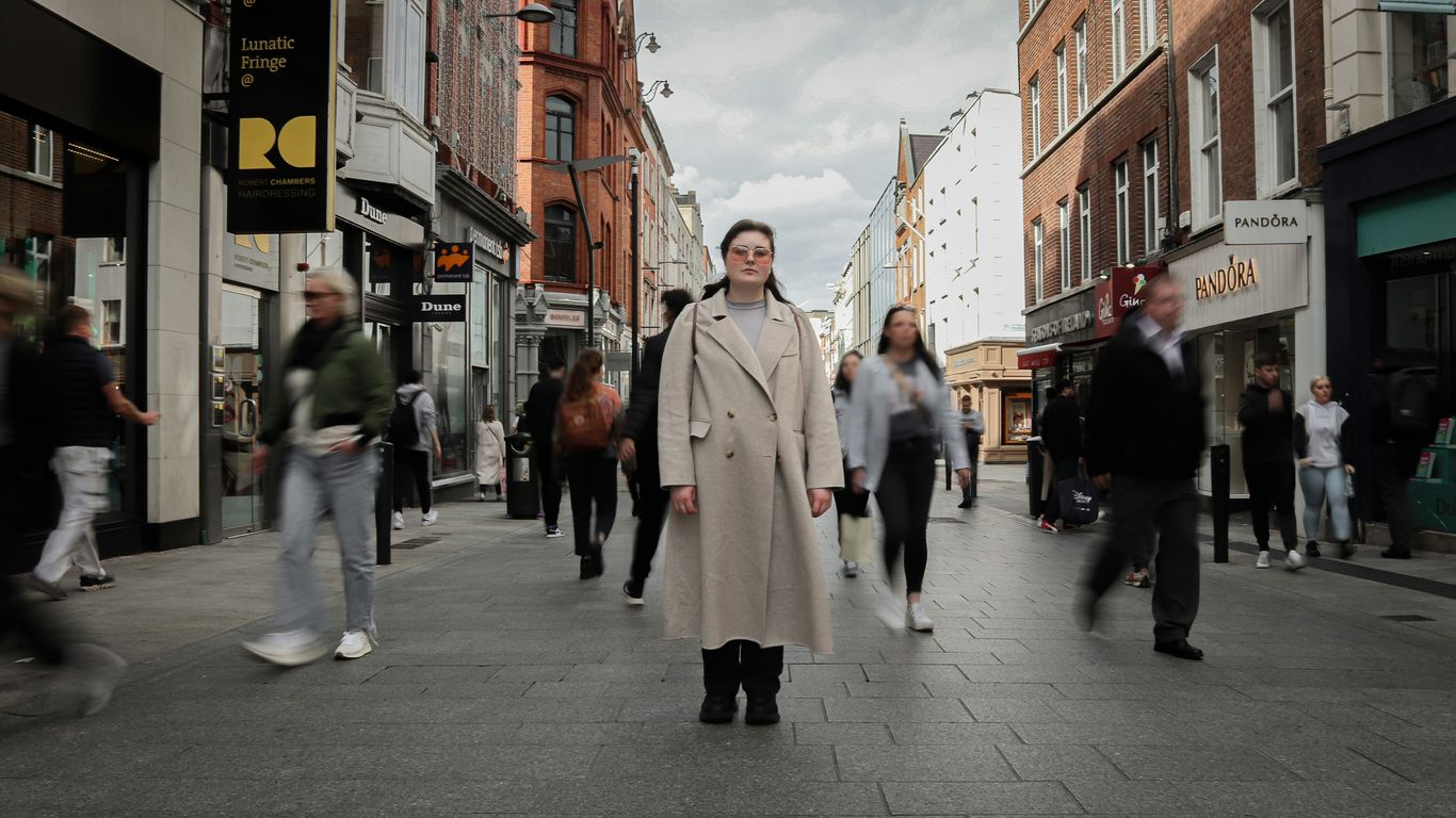 a man in a trench coat walking down a street