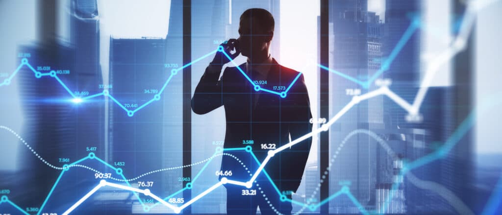 A silhouette of a person in a suit talking on the phone stands by a window with tall buildings outside, overlaid with glowing financial graphs—symbolizing the journey of building an Irish brand in today’s dynamic business landscape.