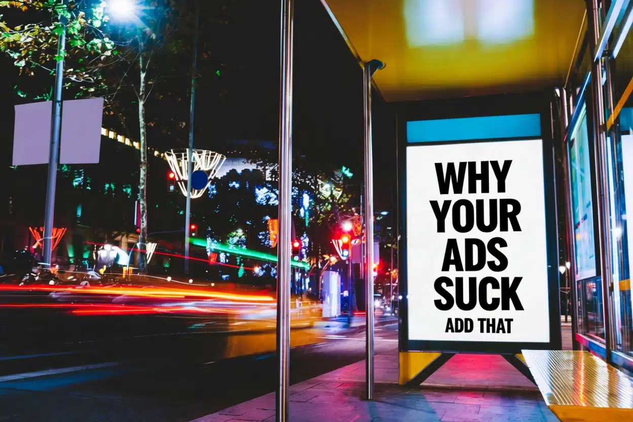 A bus stop at night features a bright digital billboard displaying the message WHY YOUR ADS SUCK ADD THAT in bold capitals, set against colorful city lights—perfect inspiration for anyone building an Irish brand in a vibrant urban scene.